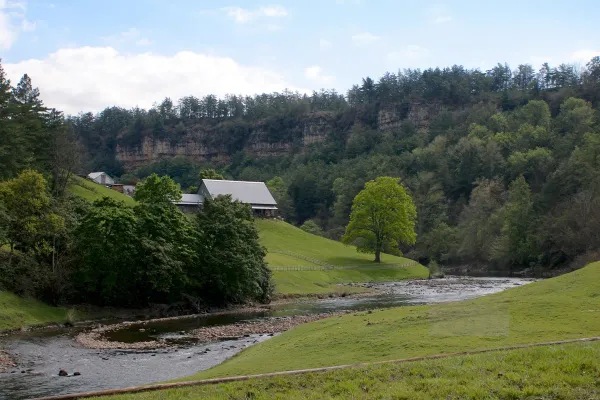 Barndominium on a ridge slope above a rocky river valley pasture in Blount County, Alabama